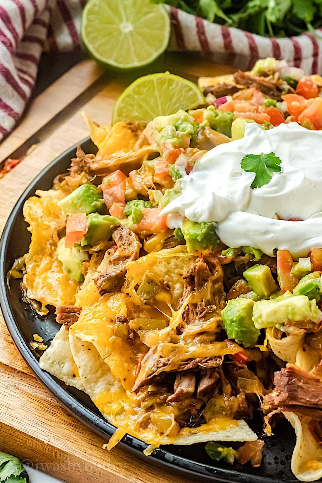 plate filled with shredded beef nachos and nacho toppings.