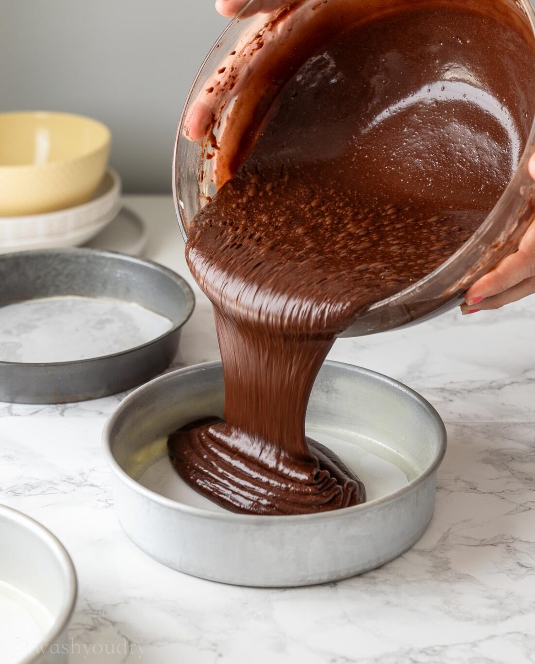 pouring chocolate cake batter into round cake pan.