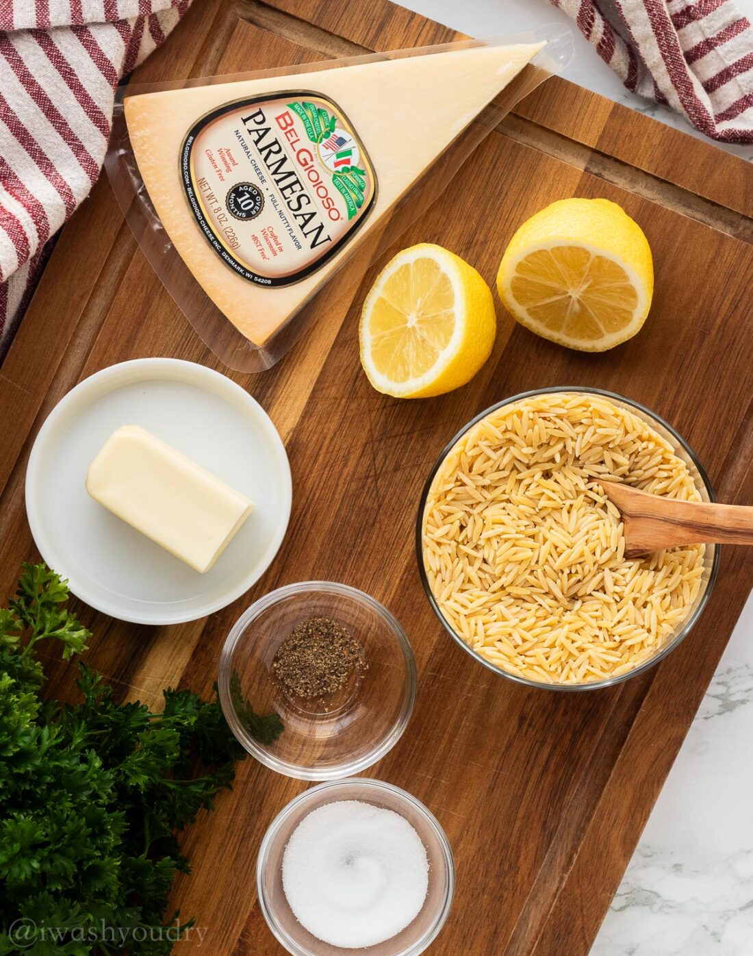 Ingredients for orzo pasta in glass bowls on wood cutting board with dish towel. 