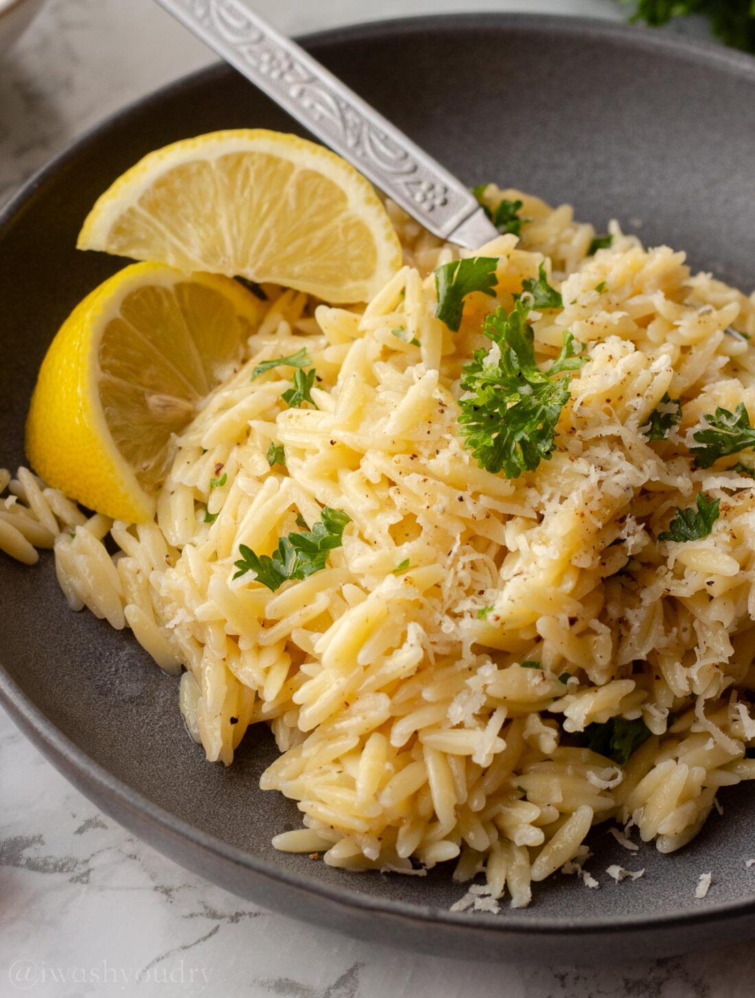 cooked orzo pasta with lemon and parmesan on black plate.