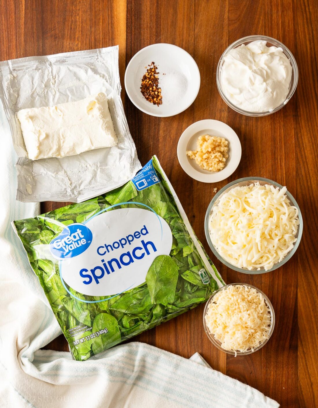 Ingredients for spinach dip on wooden surface with parmesan cheese.