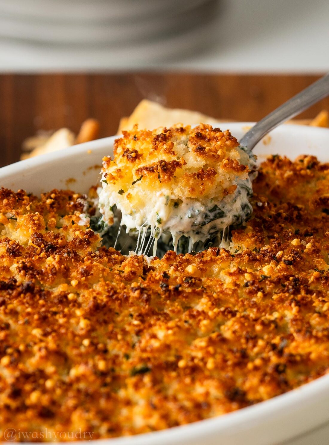spoonful of cheesy spinach dip with parmesan crust on top.