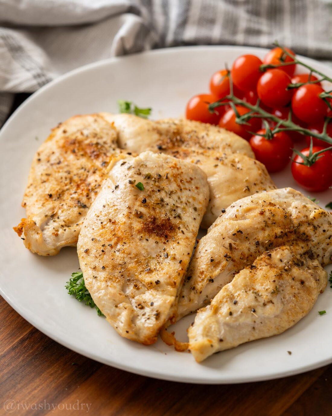 Cooked Air Fryer Chicken Breasts on white plate with tomatoes.