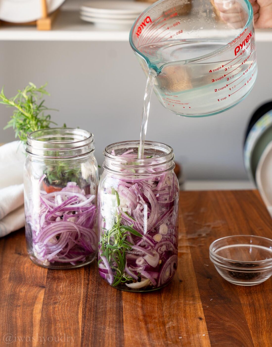 Pouring pickling liquid into jar of red onions. 