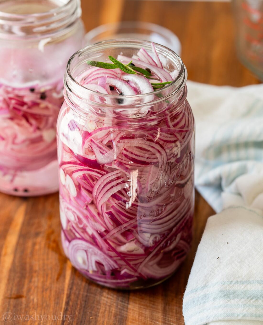 Jar of red onions with pickling liquid and rosemary. 