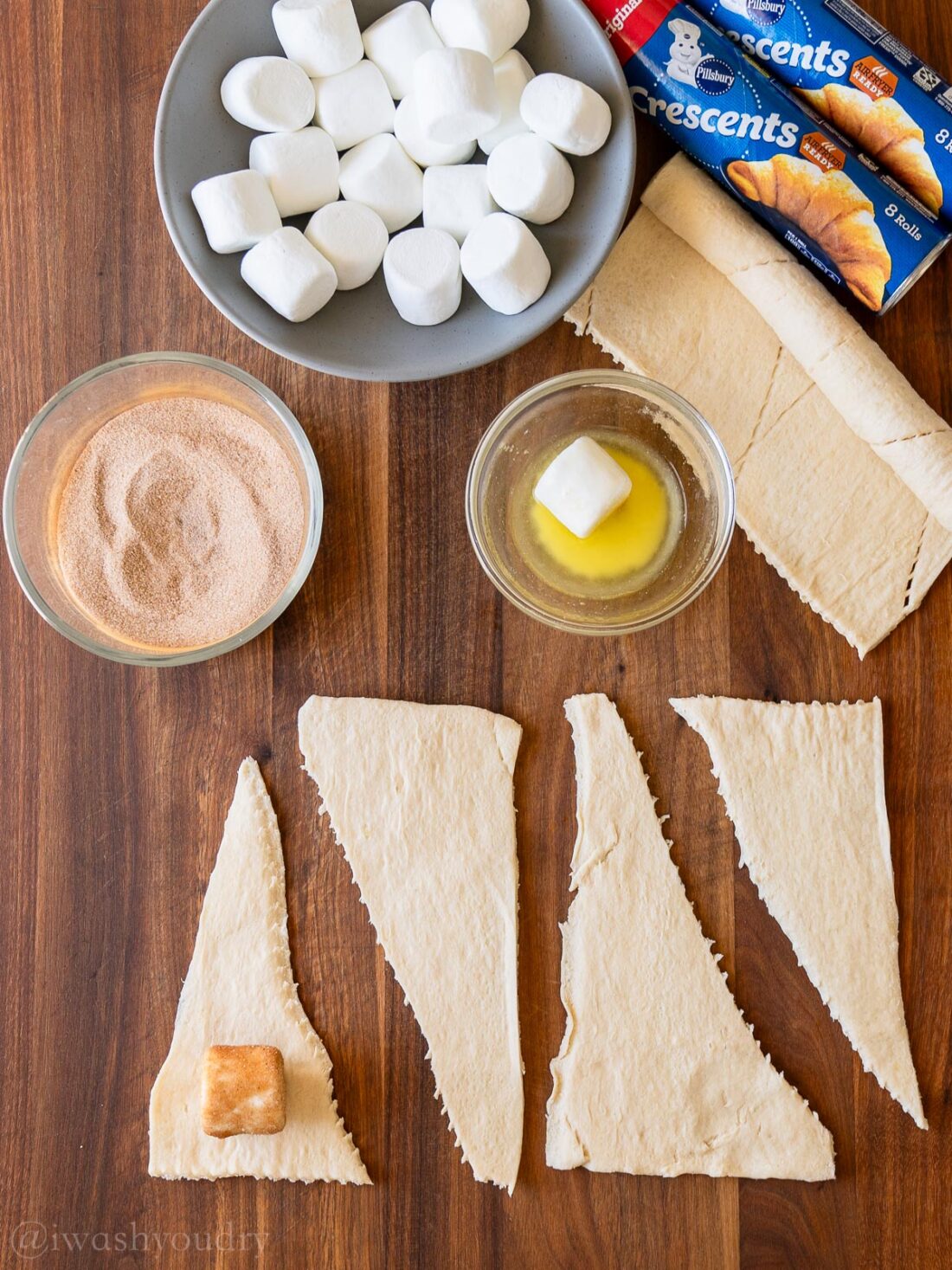 Preparing crescent rolls with marshmallows on a wooden surface.