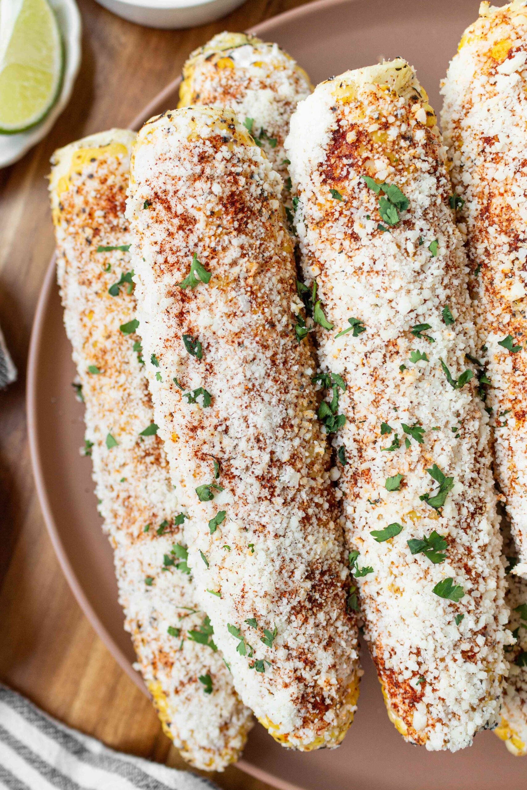 grilled street corn coated in cotija cheese and chopped cilantro on plate.