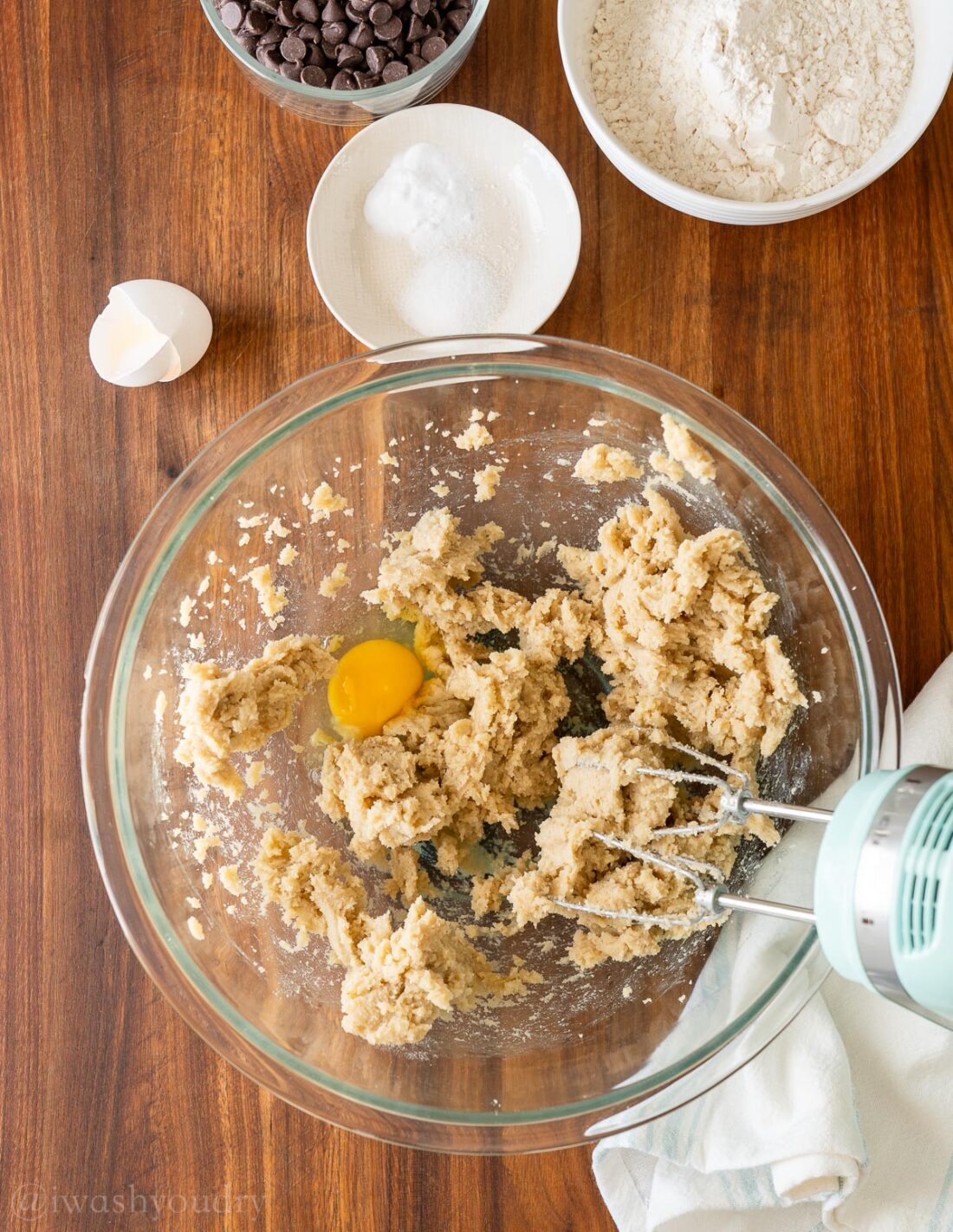 mixing cookie dough in glass bowl with egg.