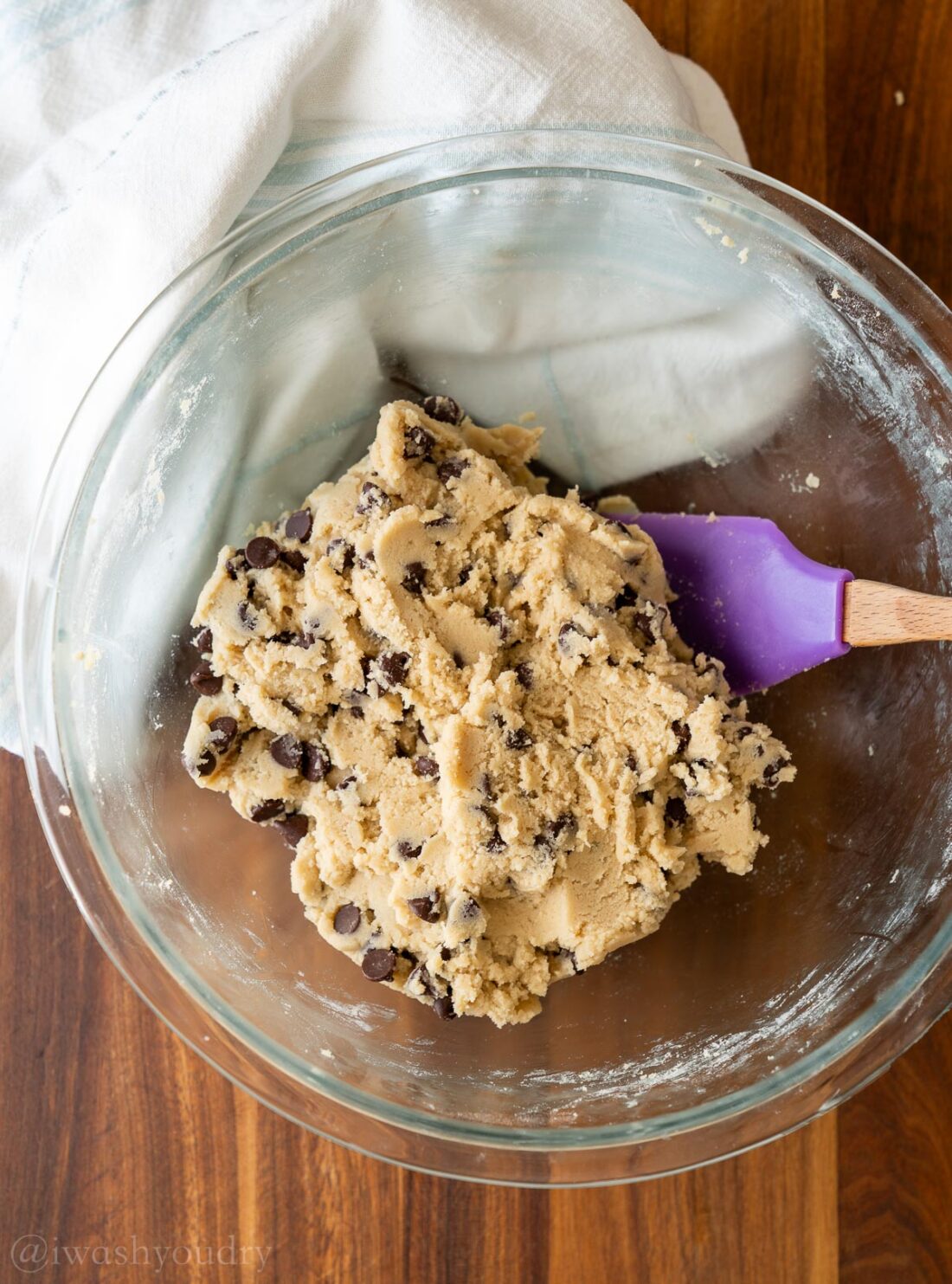 cookie dough in bowl with chocolate chips and rubber spatula.