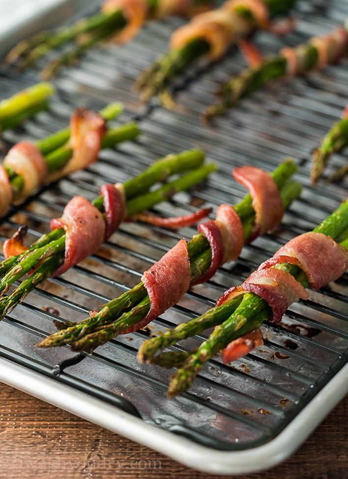 asparagus wrapped in bacon on cooking sheet.