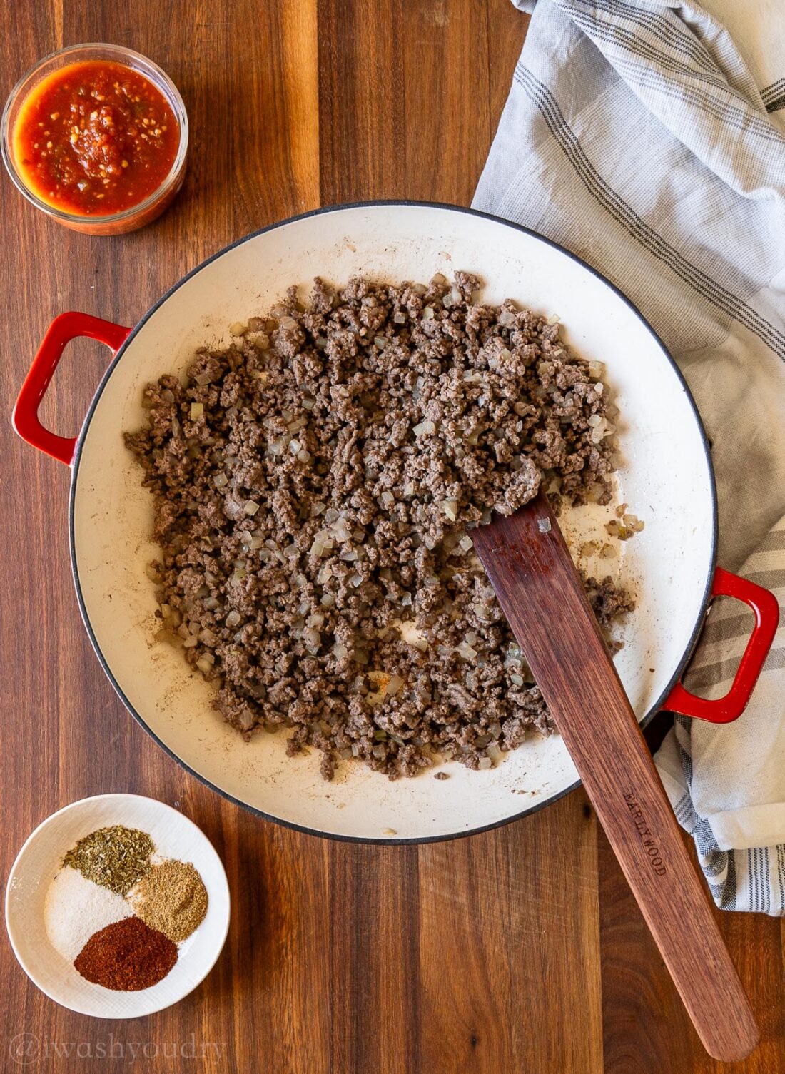 browned ground beef in skillet with wooden spoon.