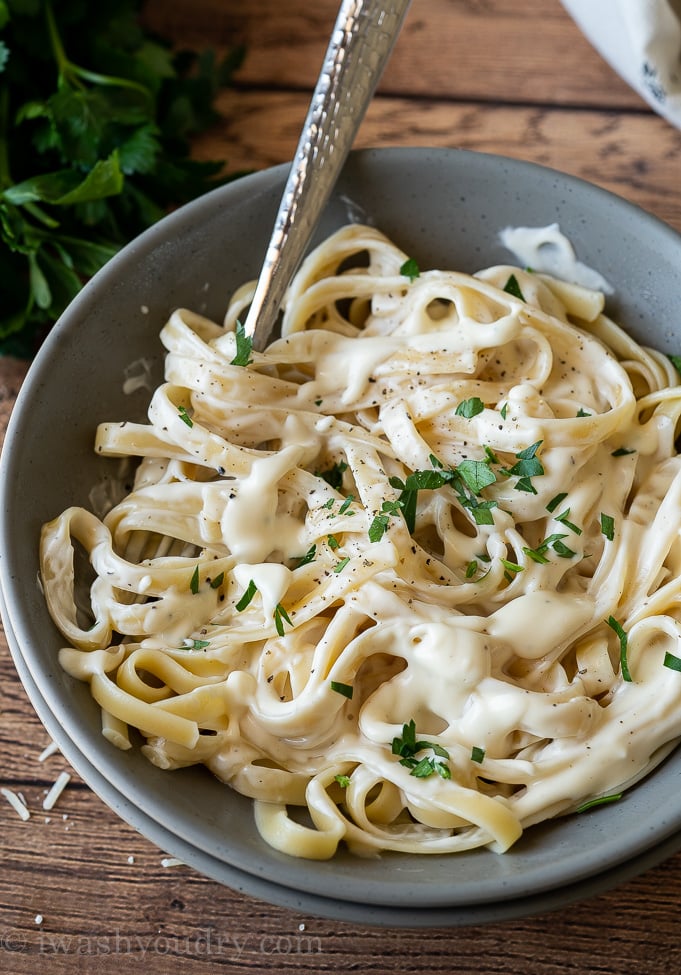 Creamy alfredo Sauce in bowl with fettuccini noodles.