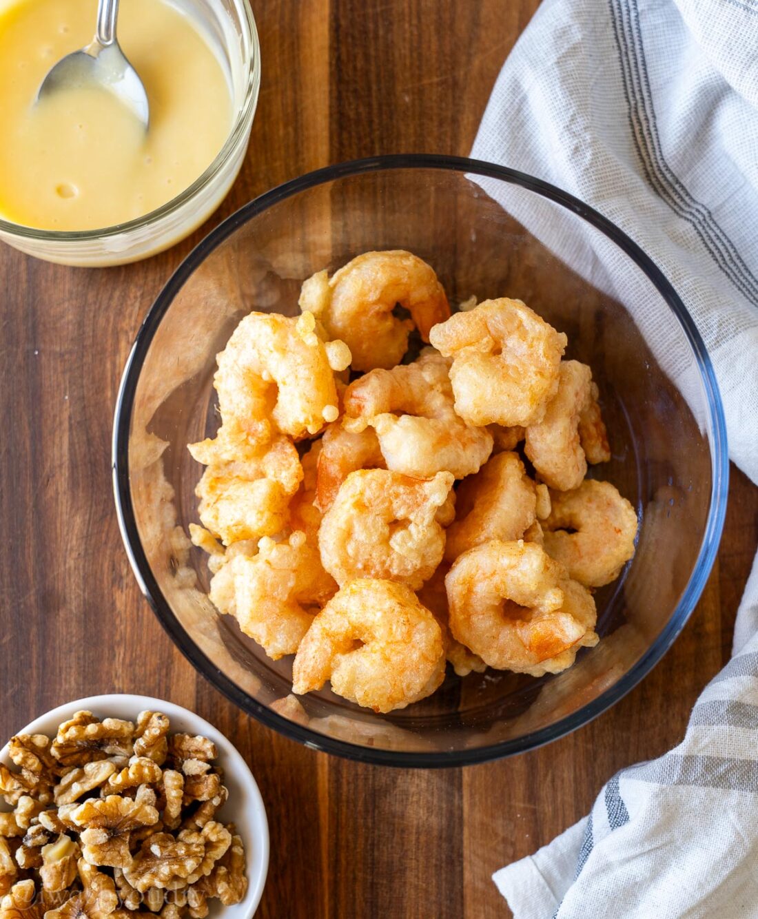 crispy shrimp in bowl with white sauce and walnuts on the side.