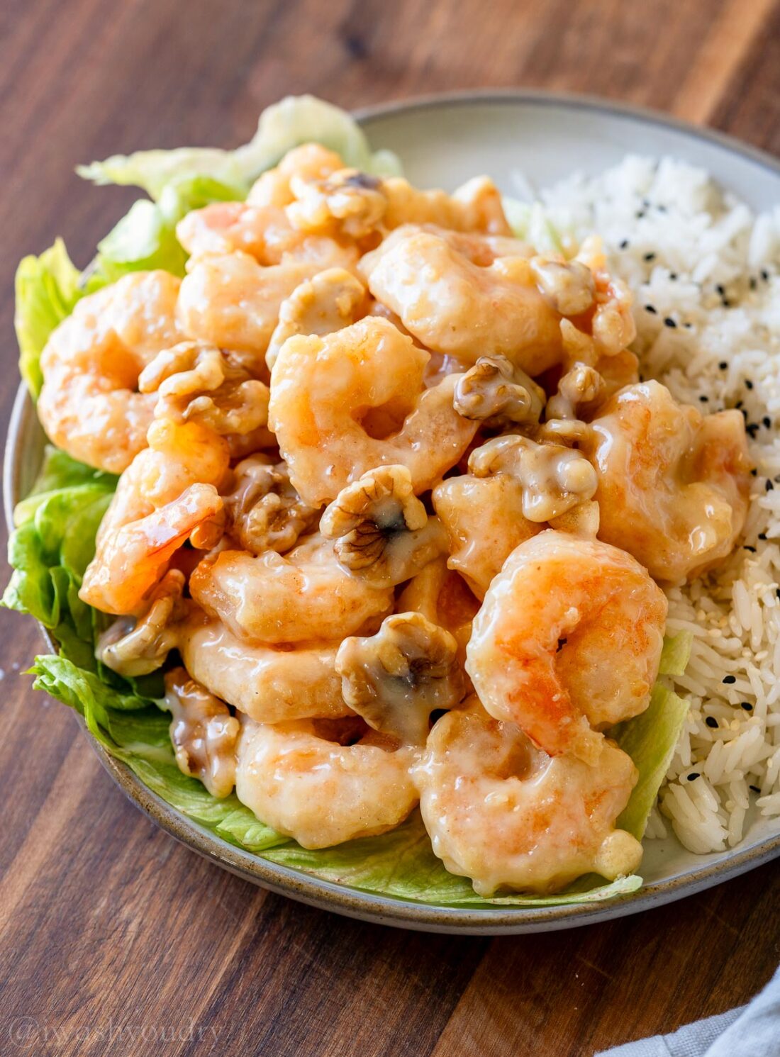 Honey Walnut Shrimp on top of a bed of lettuce with white rice on the side.
