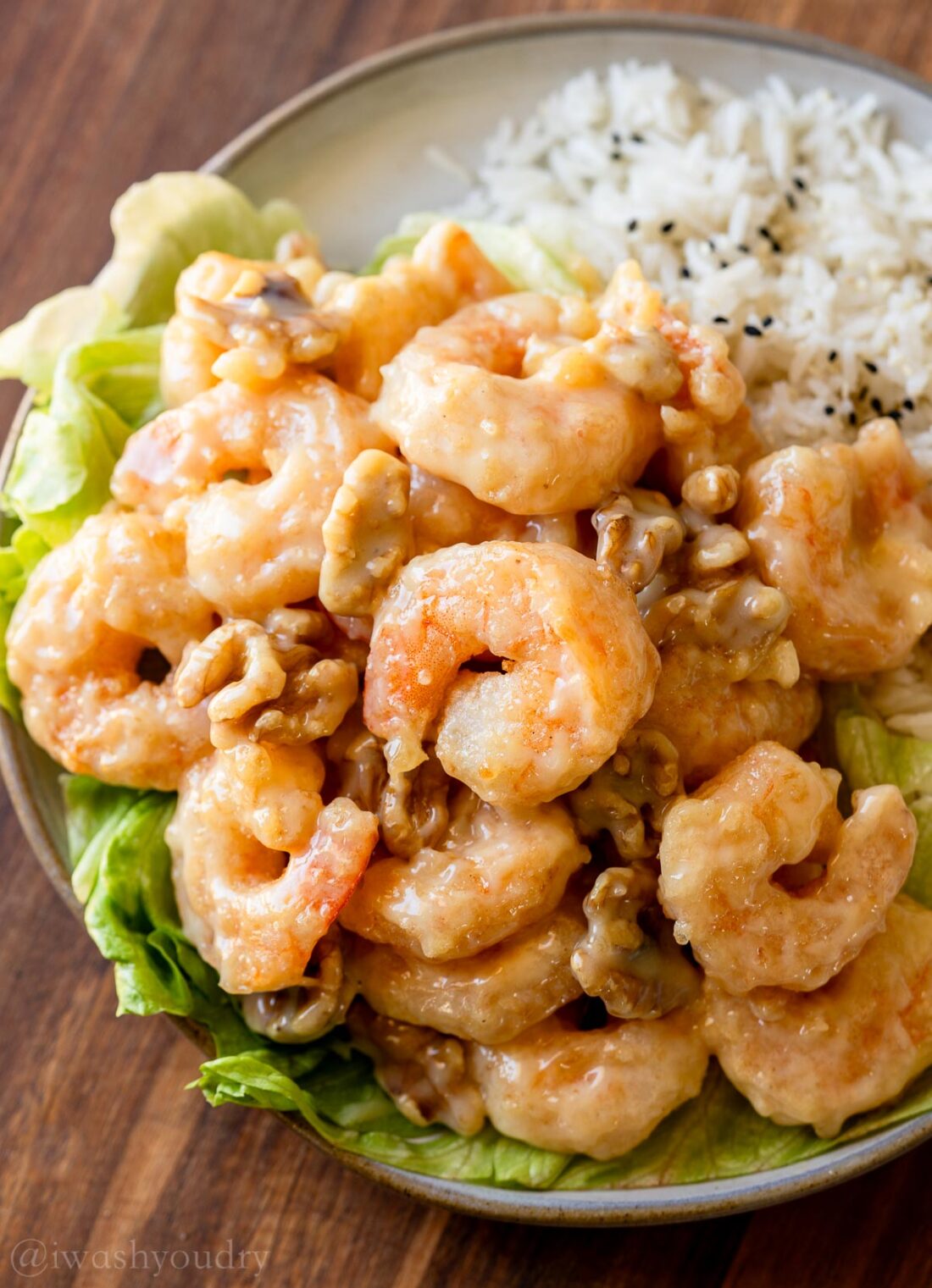 shrimp coated in sweet white sauce with walnuts on a bed of lettuce.