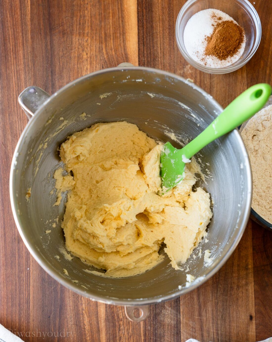 creamed butter and sugar in mixing bowl with green spatula.