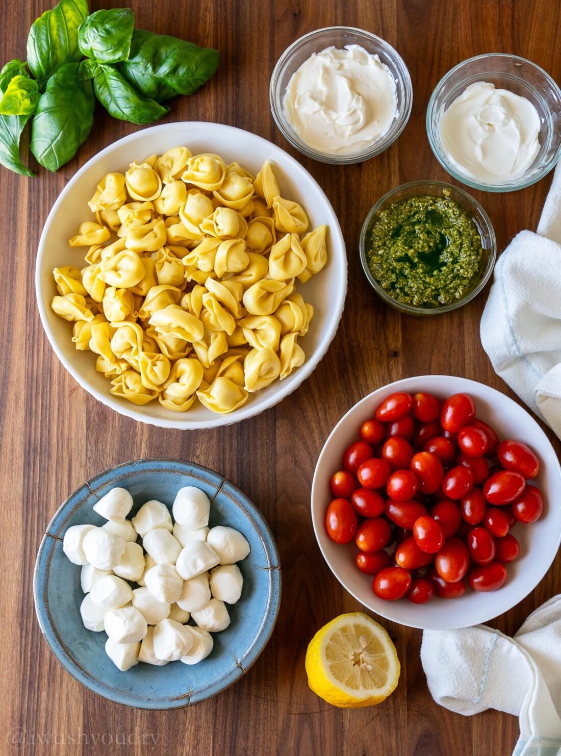 Ingredients laid out on a wooden surface with tortellini, mozzarella and tomatoes.