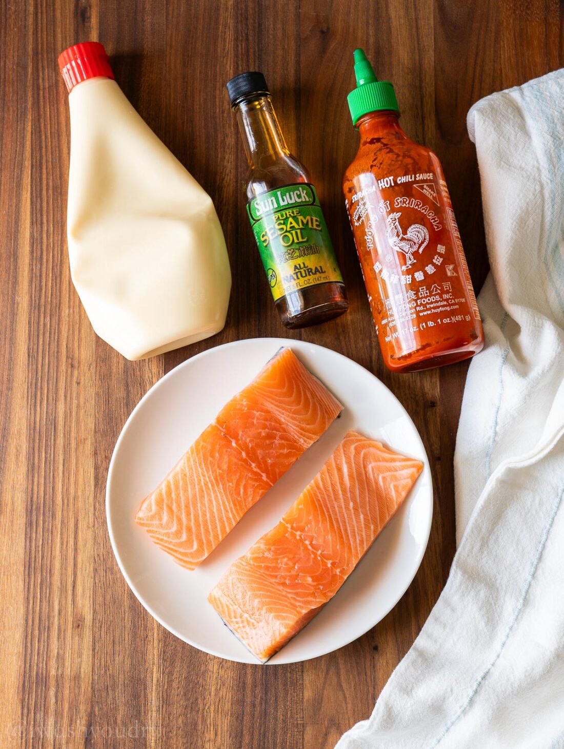 ingredients laid out on wooden surface with salmon and mayo.