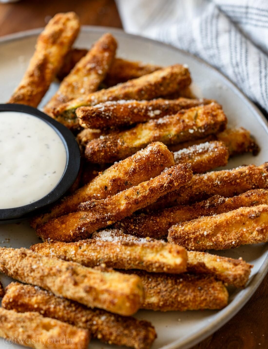 plate of golden brown zucchini fries with ranch dressing.