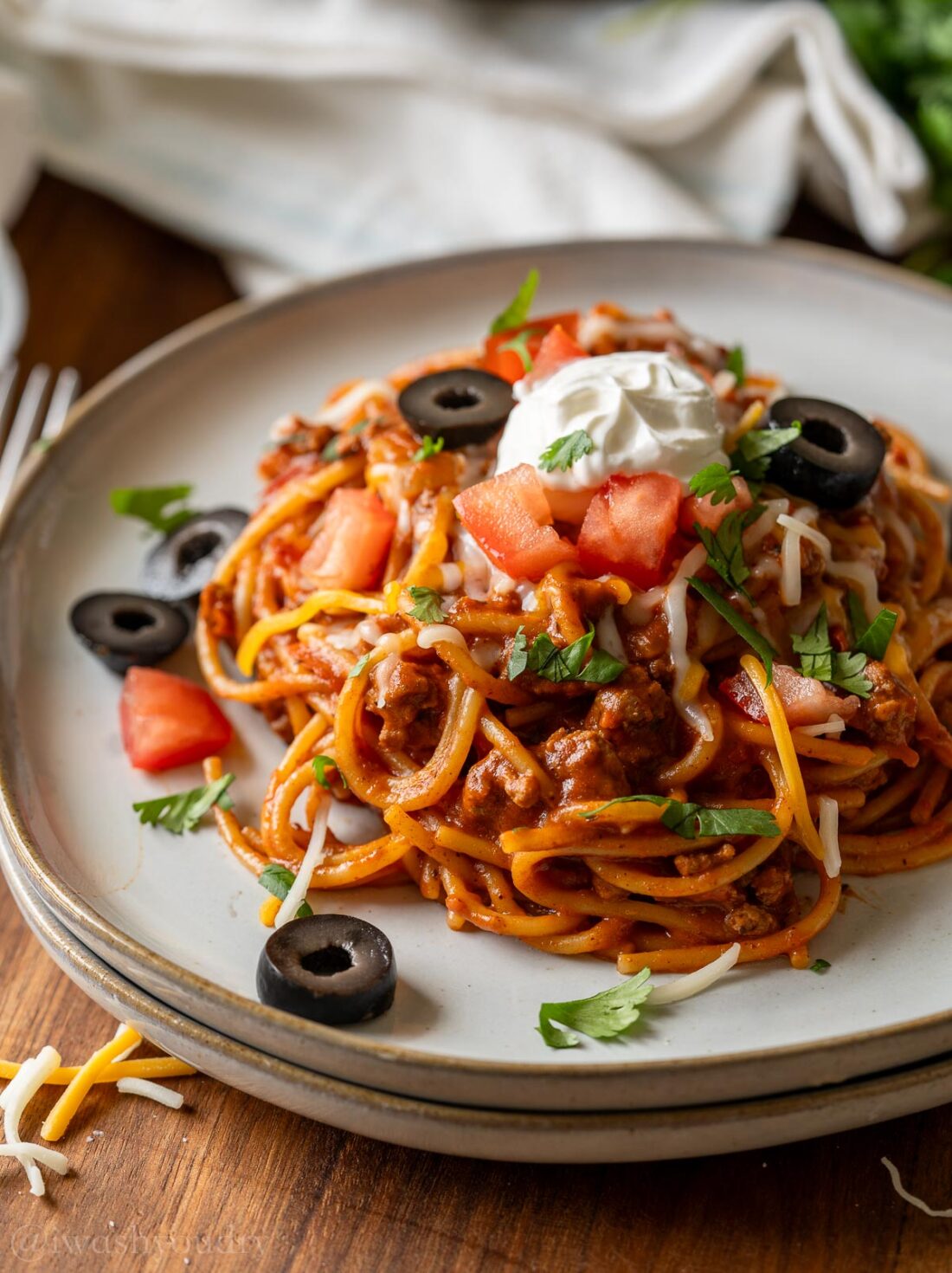 plate of spaghetti with taco meat and toppings.