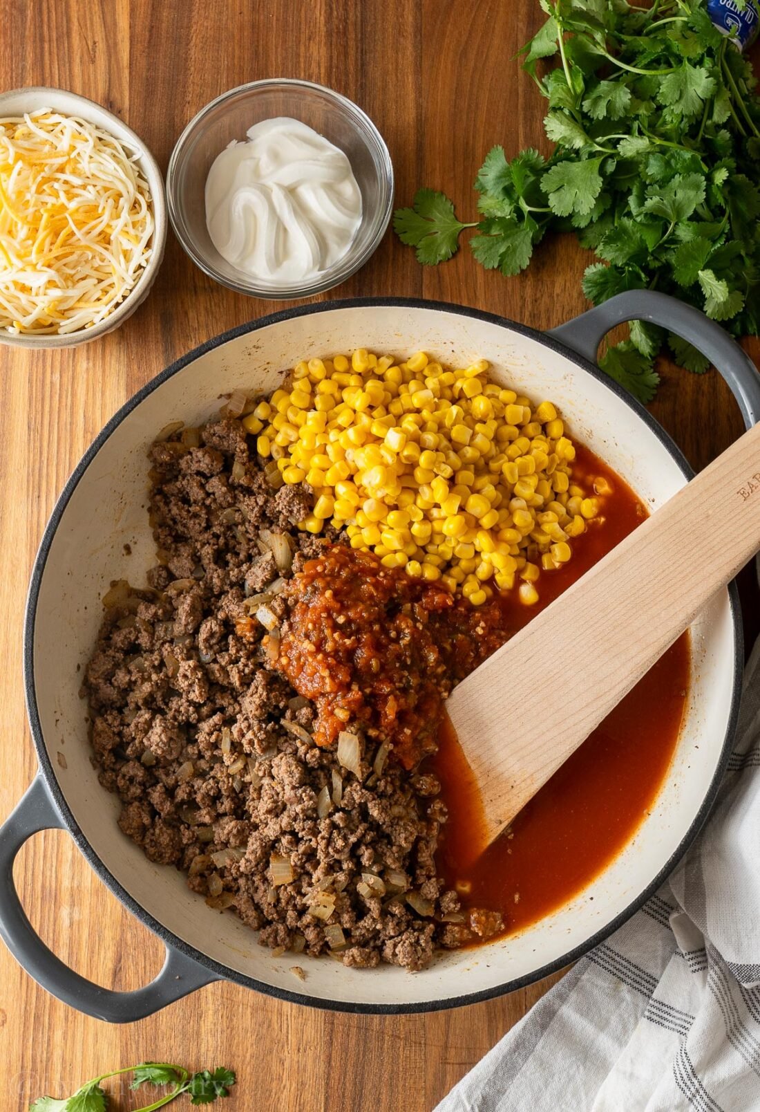 ground beef with enchilada sauce, salsa and corn in skillet.