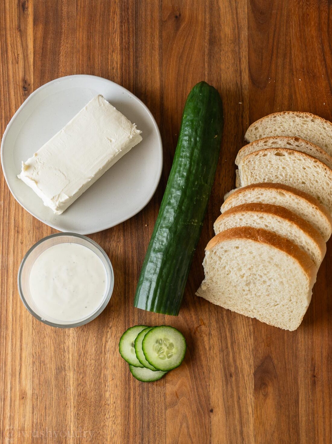 ingredients for sandwiches with cucumbers on wooden surface.