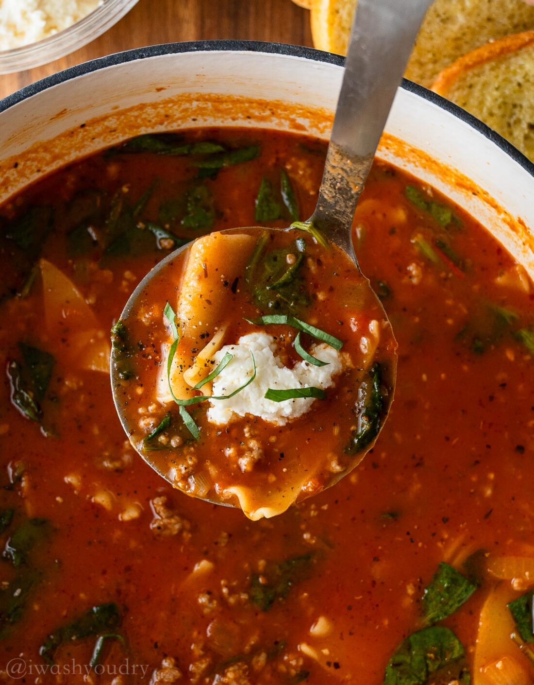 ladle of soup with ricotta dumpling on top in big pot.