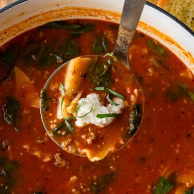 ladle of soup with ricotta dumpling on top in big pot.