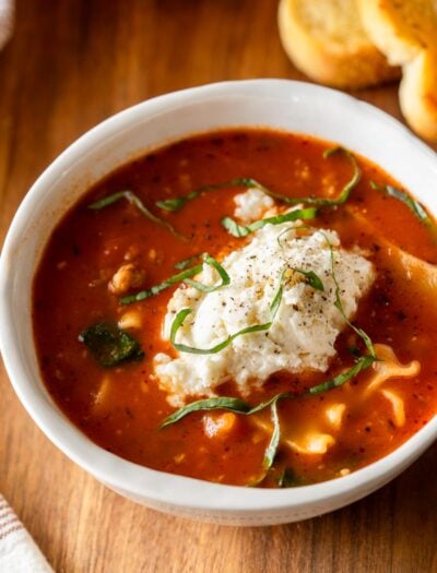 bowl of lasagna soup with ricotta cheese dumpling on top.