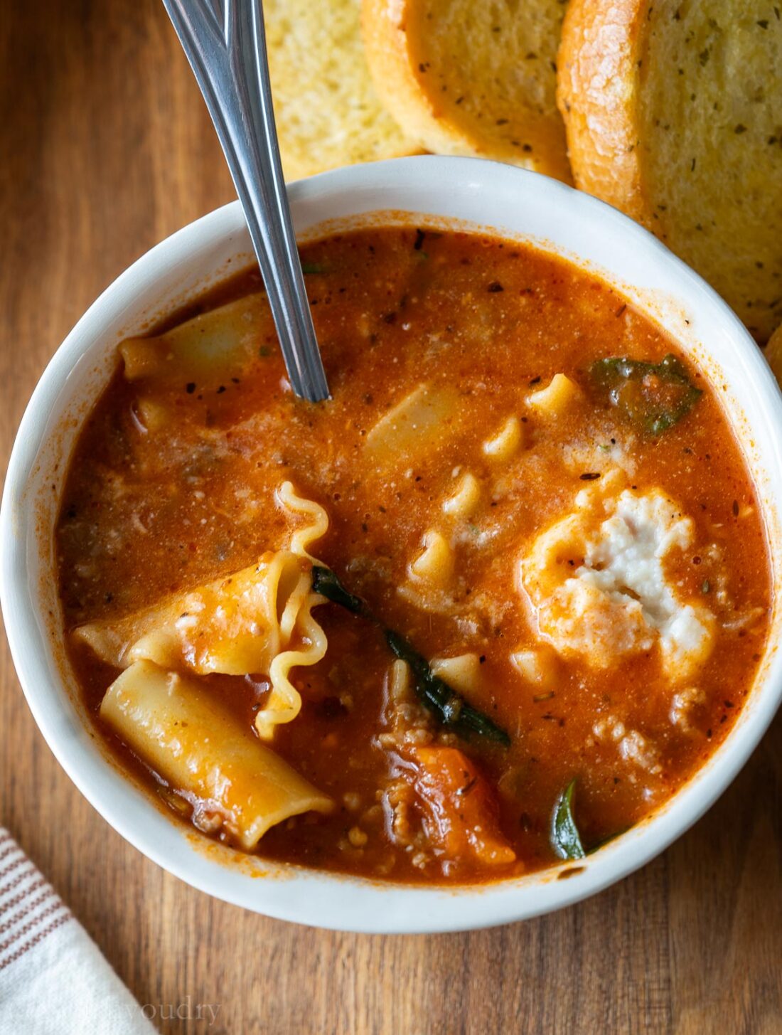 stirred up lasagna soup in bowl with spoon.