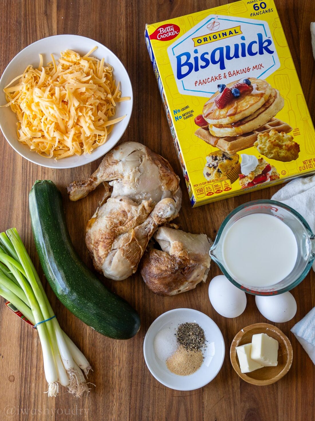 ingredients for zucchini muffins on wooden surface with bisquick mix.