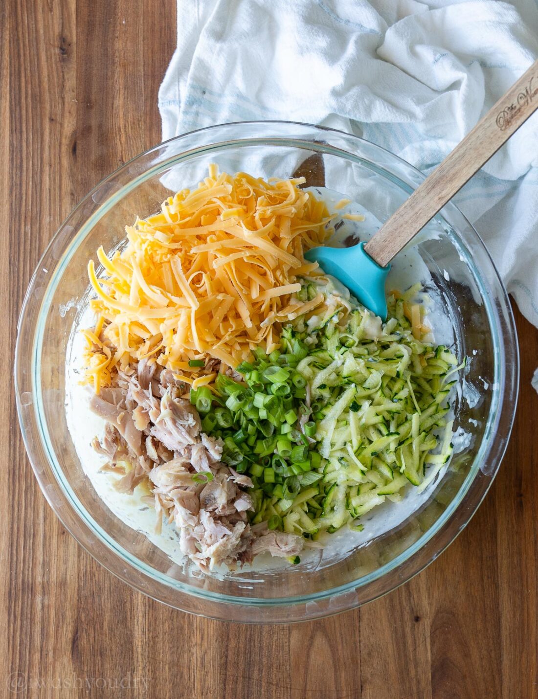 mixing ingredients in glass bowl with wooden spoon.