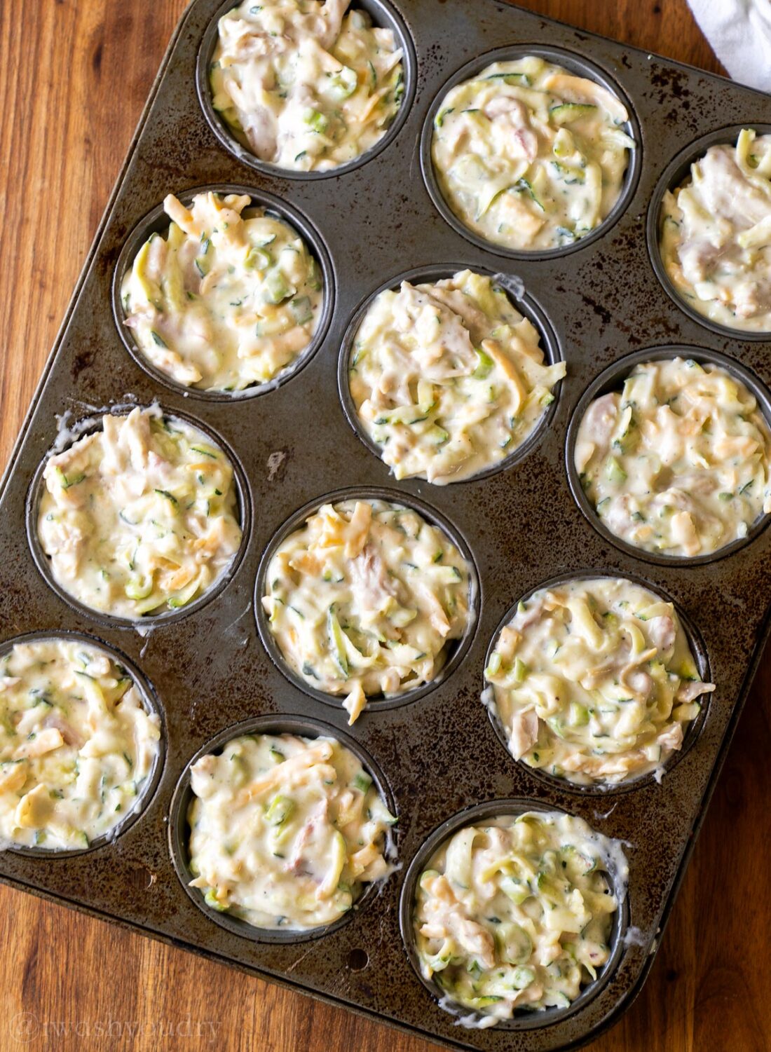 muffin batter in pan on wooden surface.