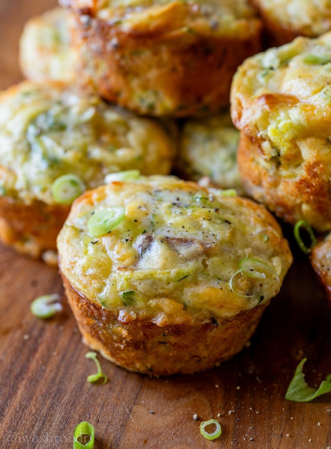 cheesy zucchini muffins on wooden surface.