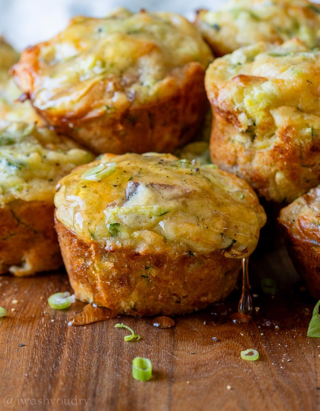 chicken muffins placed on wood surface with drizzle of honey running down sides.