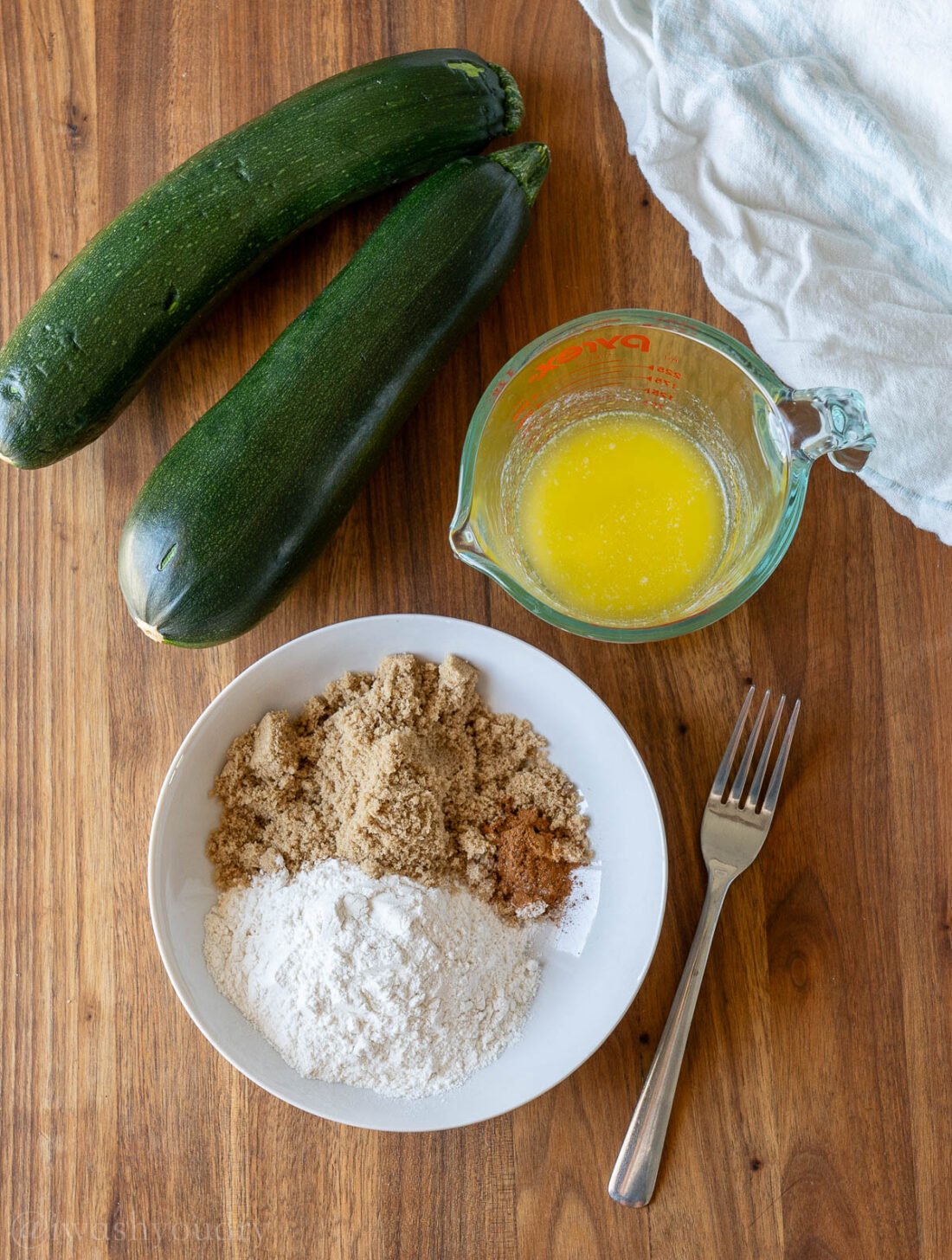 crumb topping ingredients in white bowl with zucchini nearby.