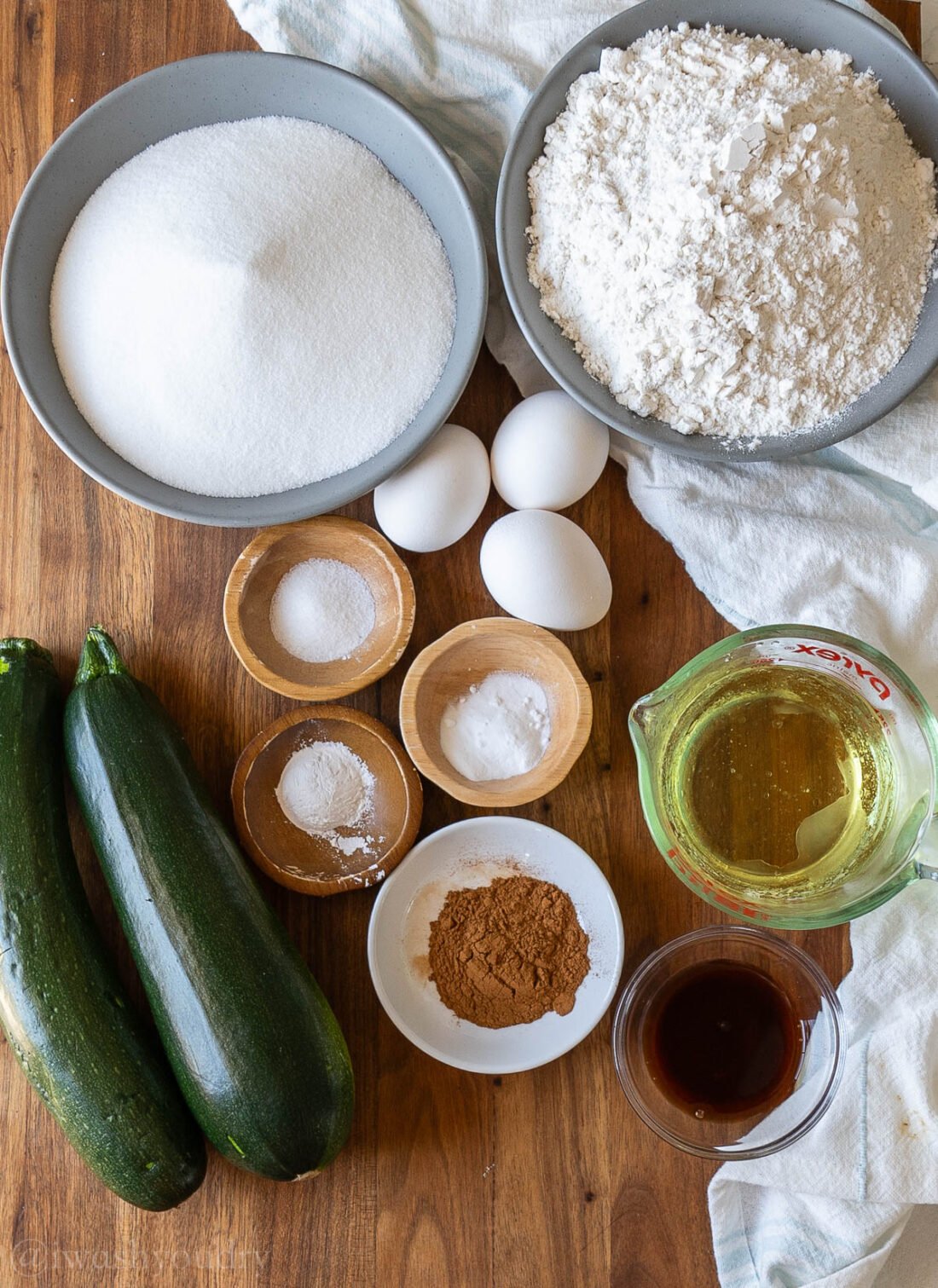 ingredients for zucchini muffins on wooden surface.