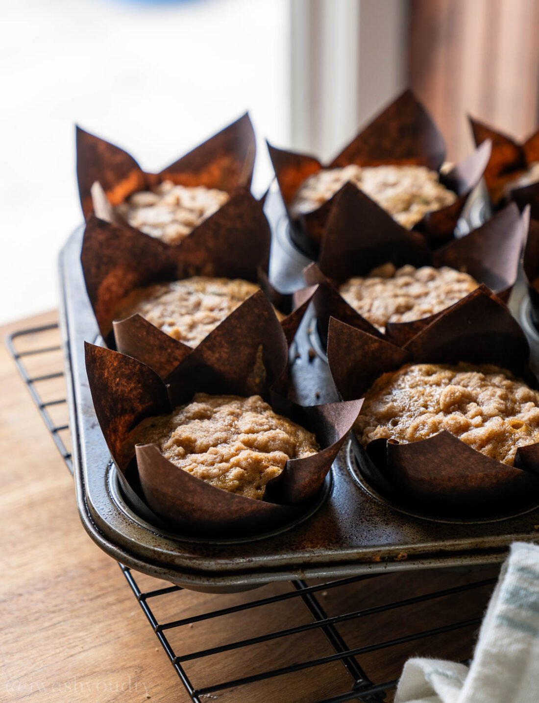 zucchini muffins in brown paper liners on wire rack.