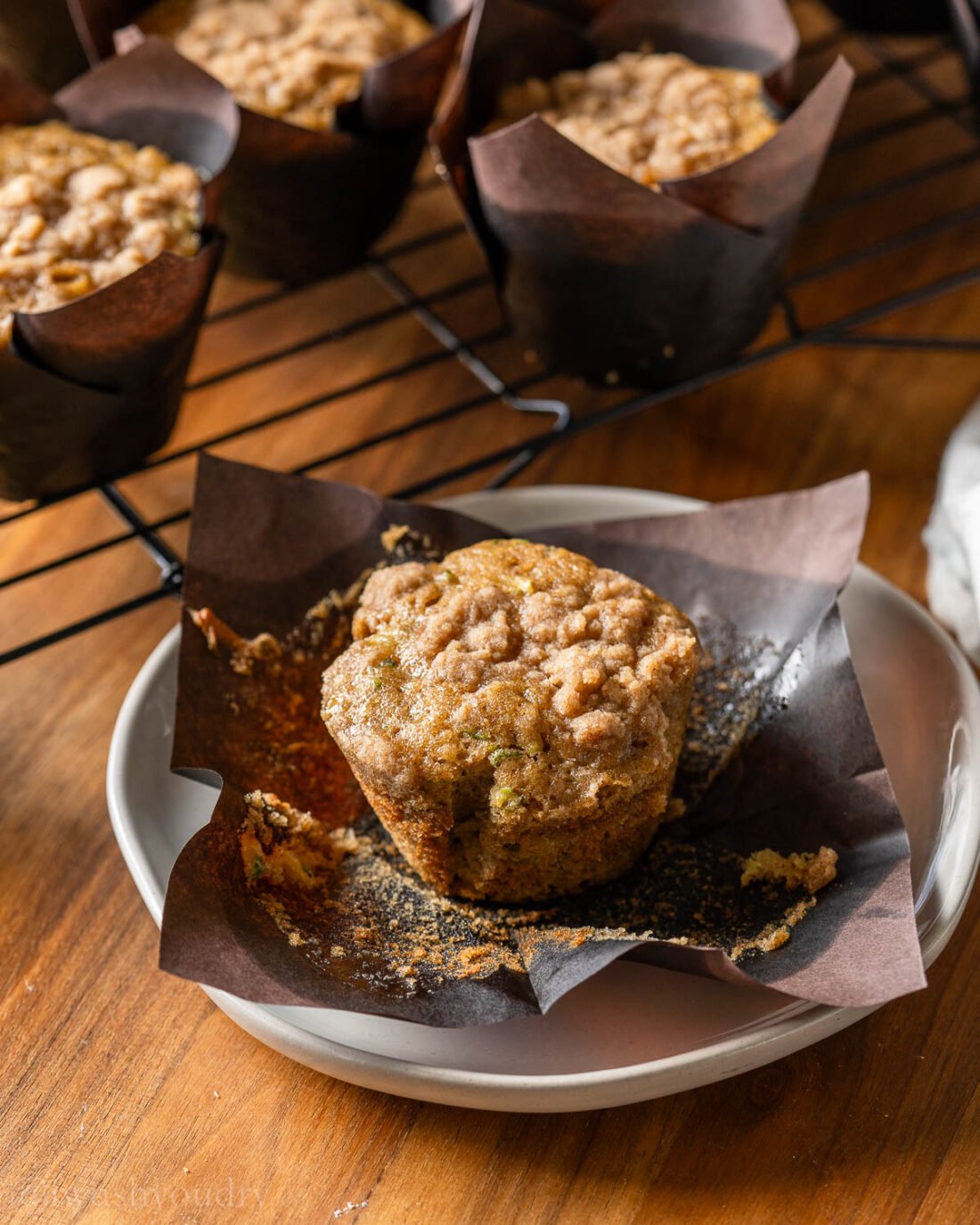 unwrapped muffin on plate with brown paper wrapper around it.