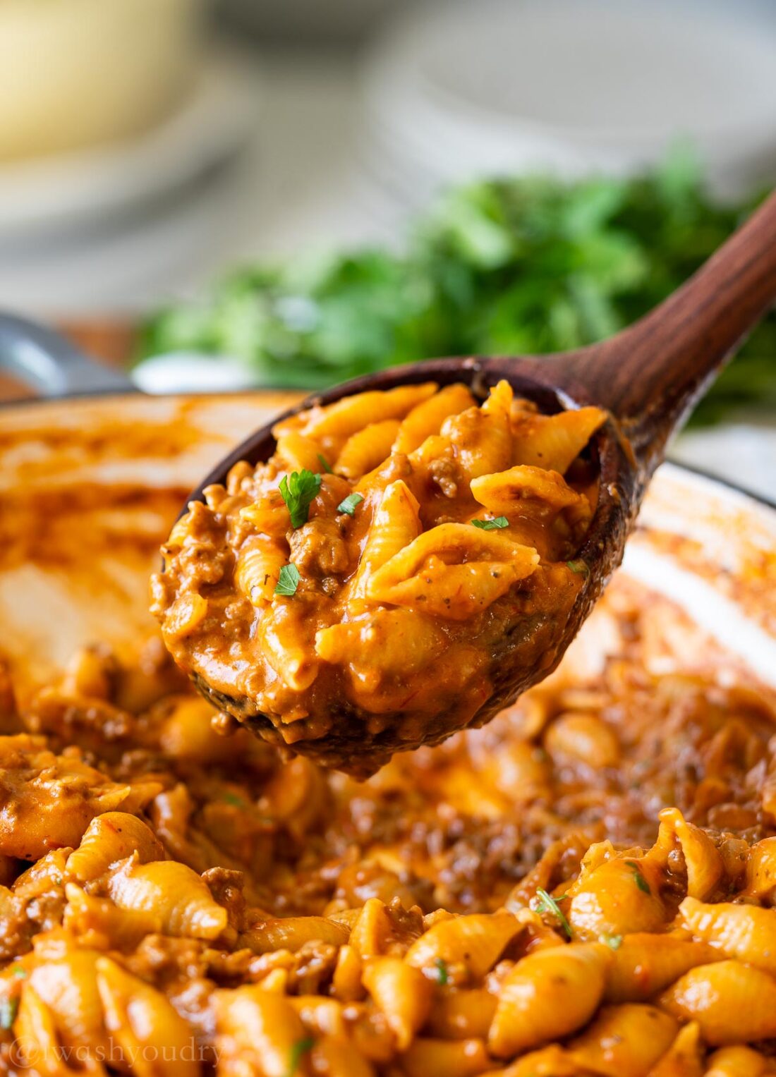 wooden spoonful of shells and ground beef in tomato sauce.
