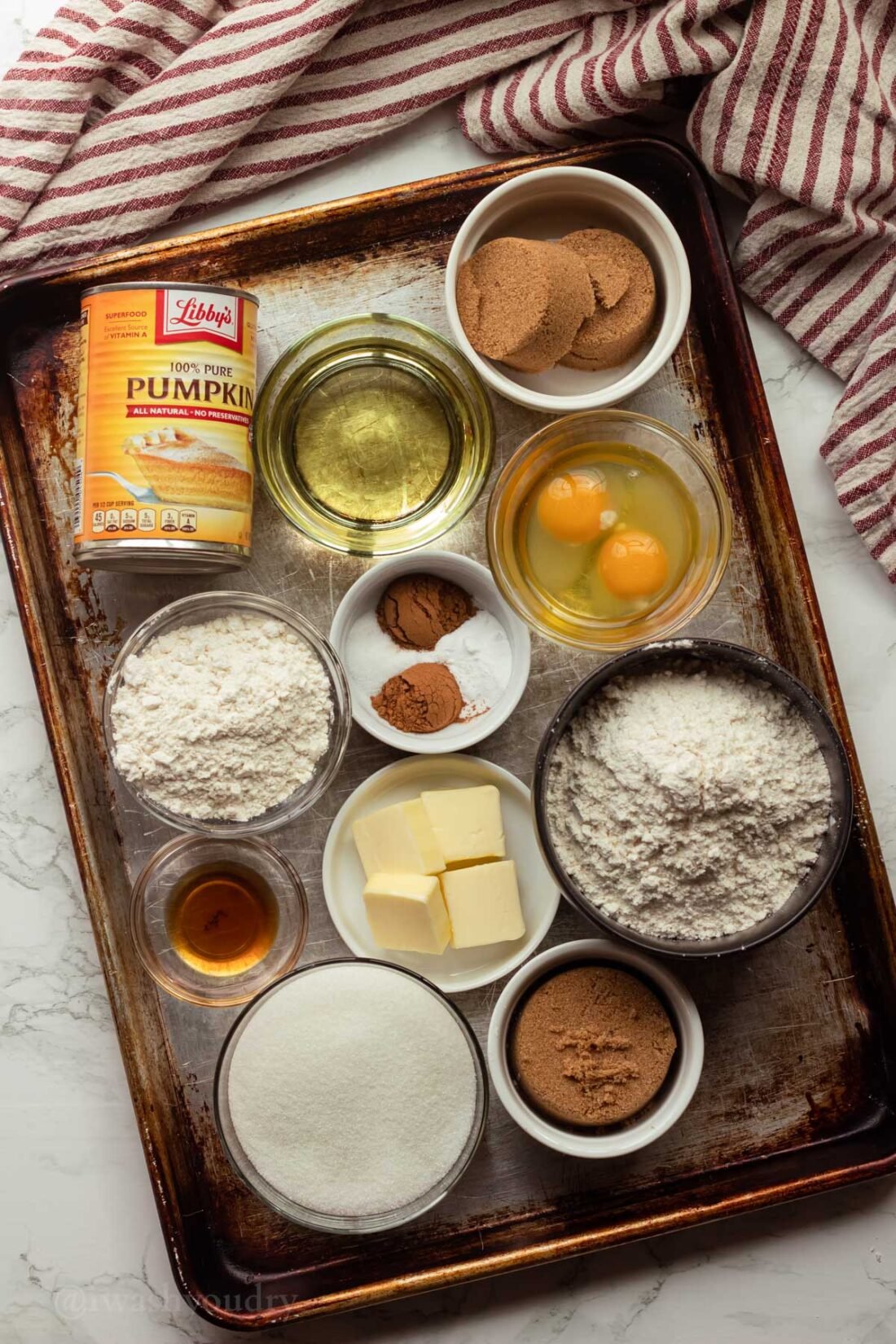 metal sheet pan with ingredients for muffins in small bowls.