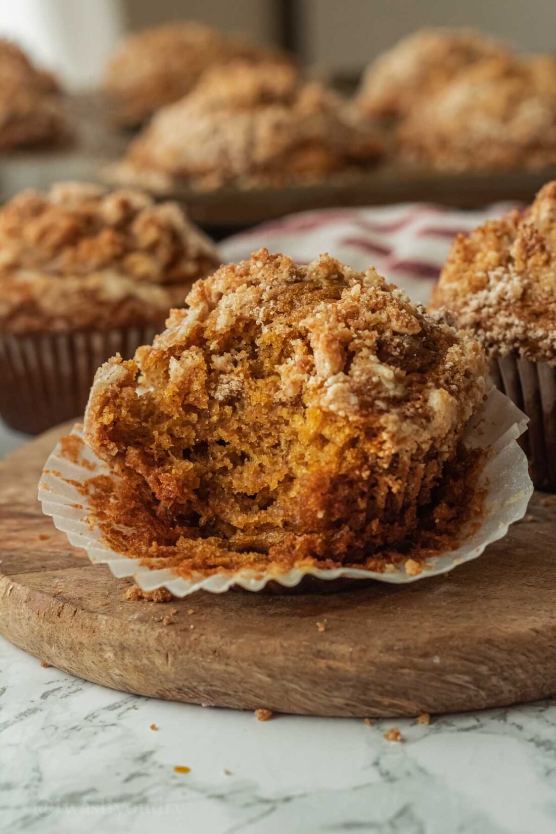 bite taken out of pumpkin crumb muffin on wooden surface.