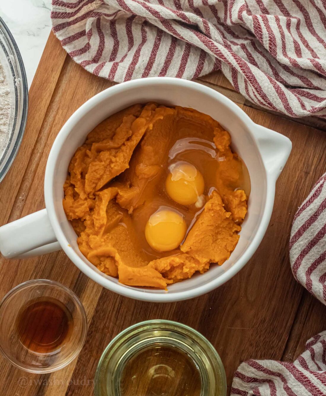 pumpkin puree with eggs in white mixing bowl.