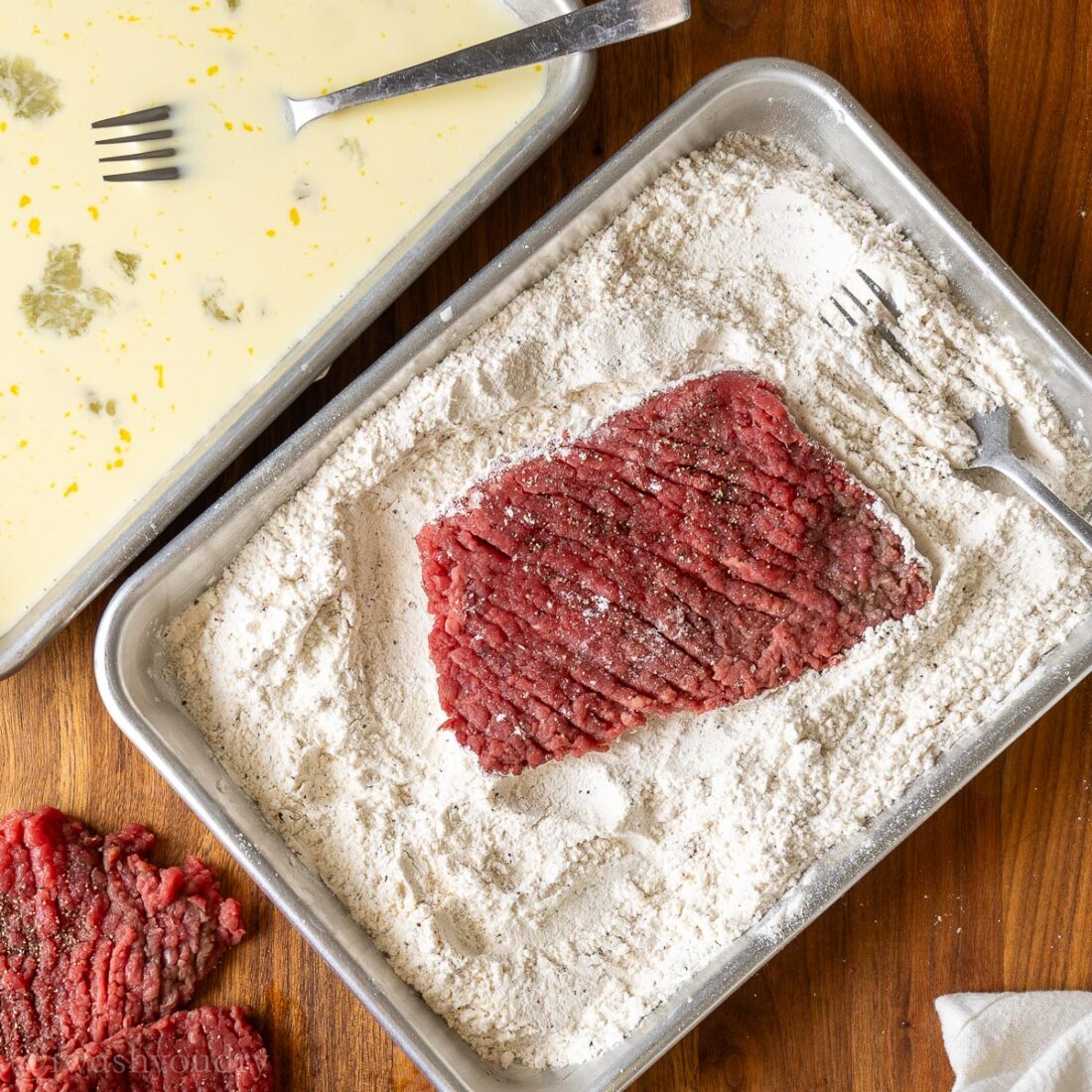 cube steak in pan with flour.