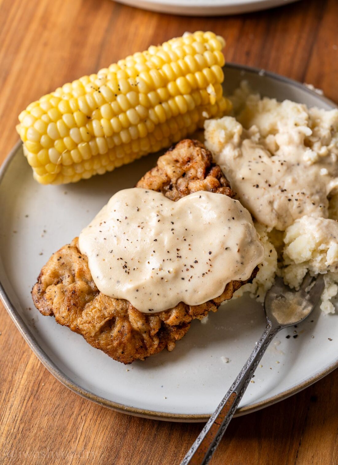 plate with chicken fried steak and gravy on top.