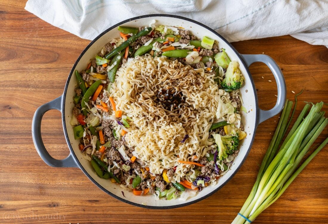 skillet filled with ground beef and ramen noodles, sauce on top.