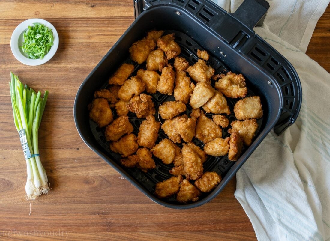 breaded chicken pieces in an air fryer basket.