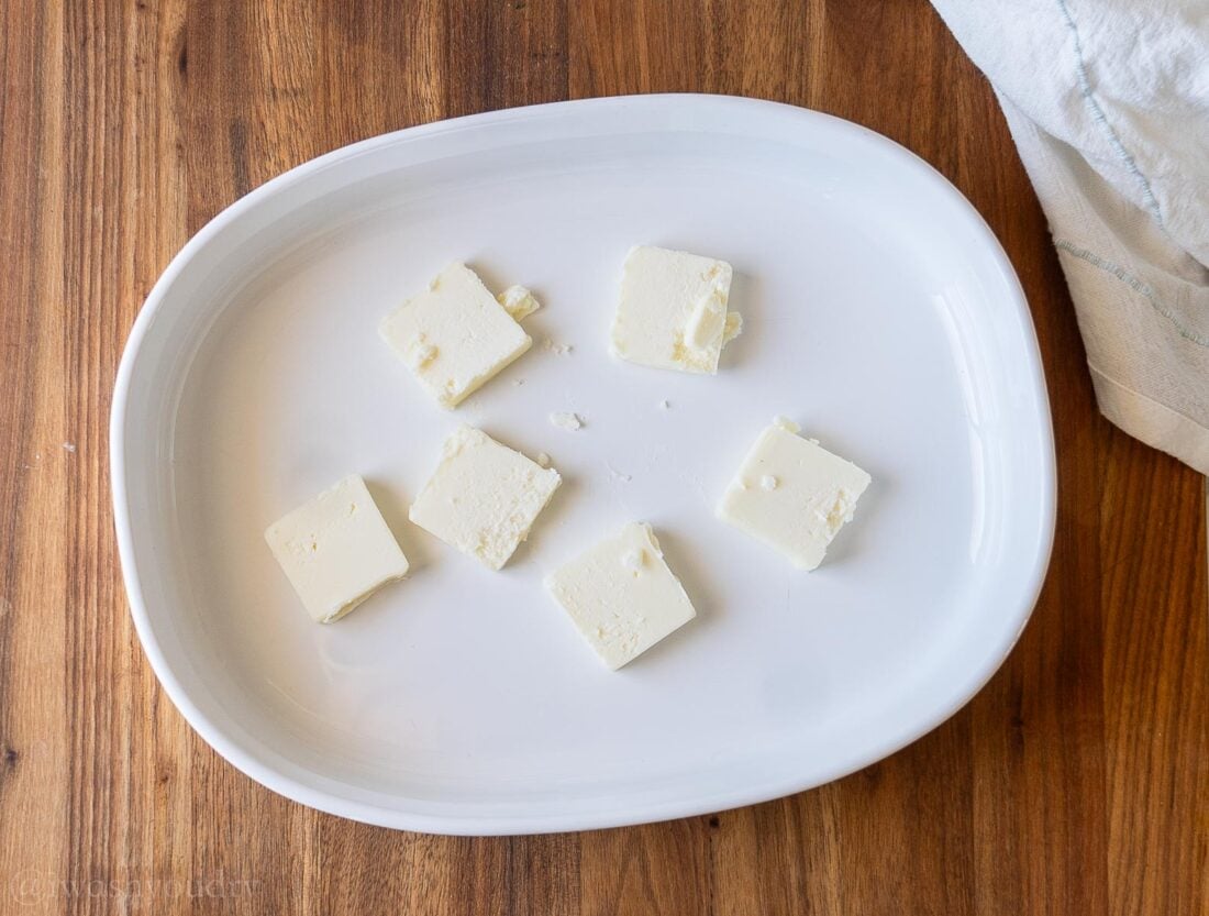 butter slices in baking dish on wooden surface.