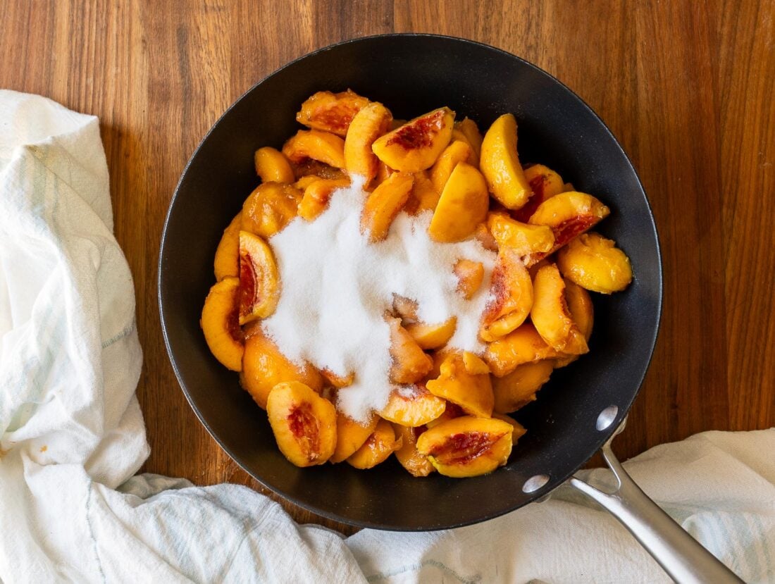 fresh peaches in a pot with sugar on top.