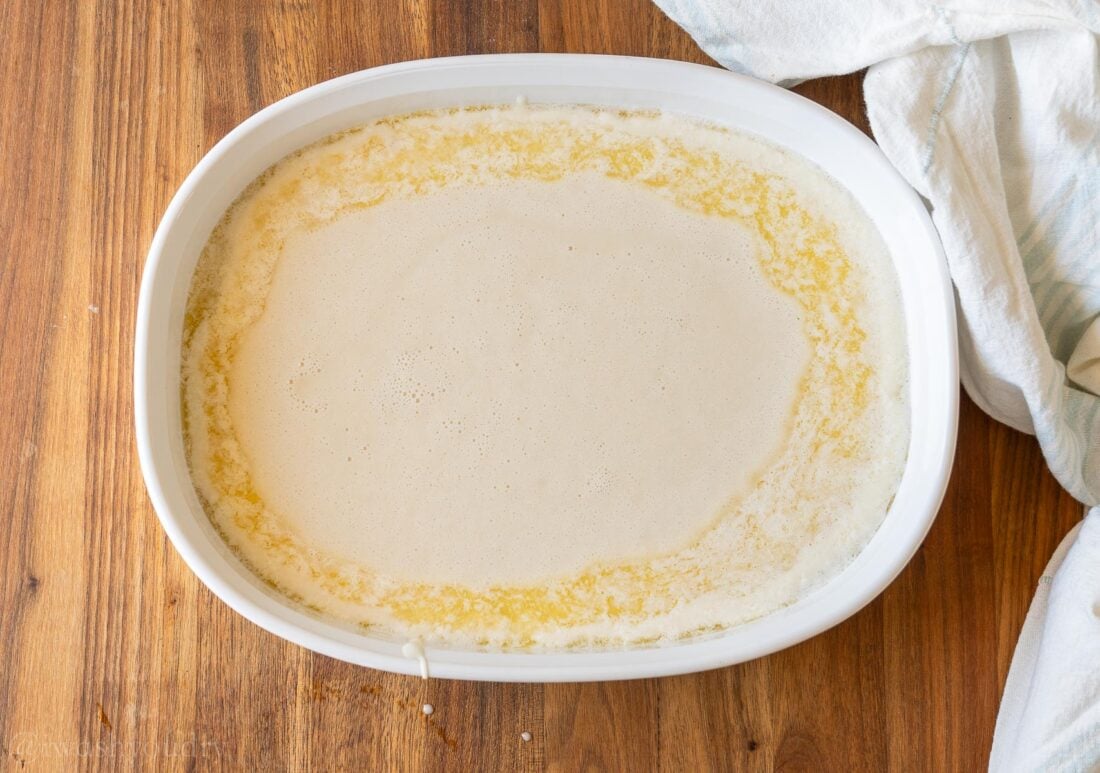 cobbler batter in baking dish with melted butter around the edges.
